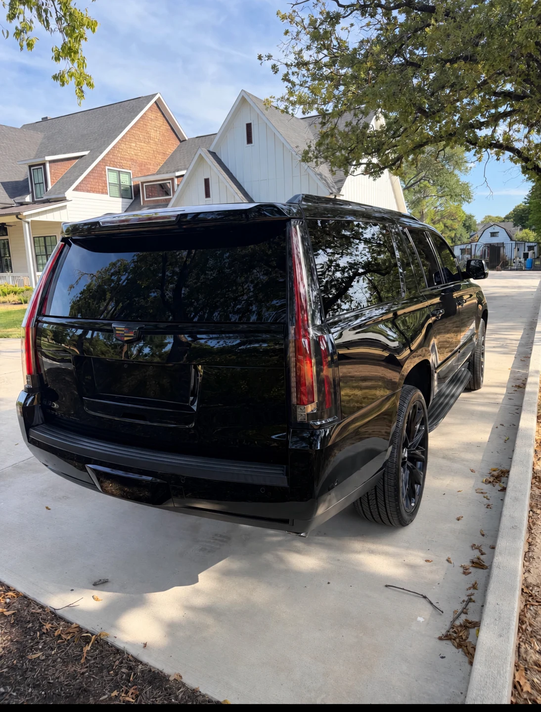 Black Cadillac Escalade ESV parked beside a residential driveway