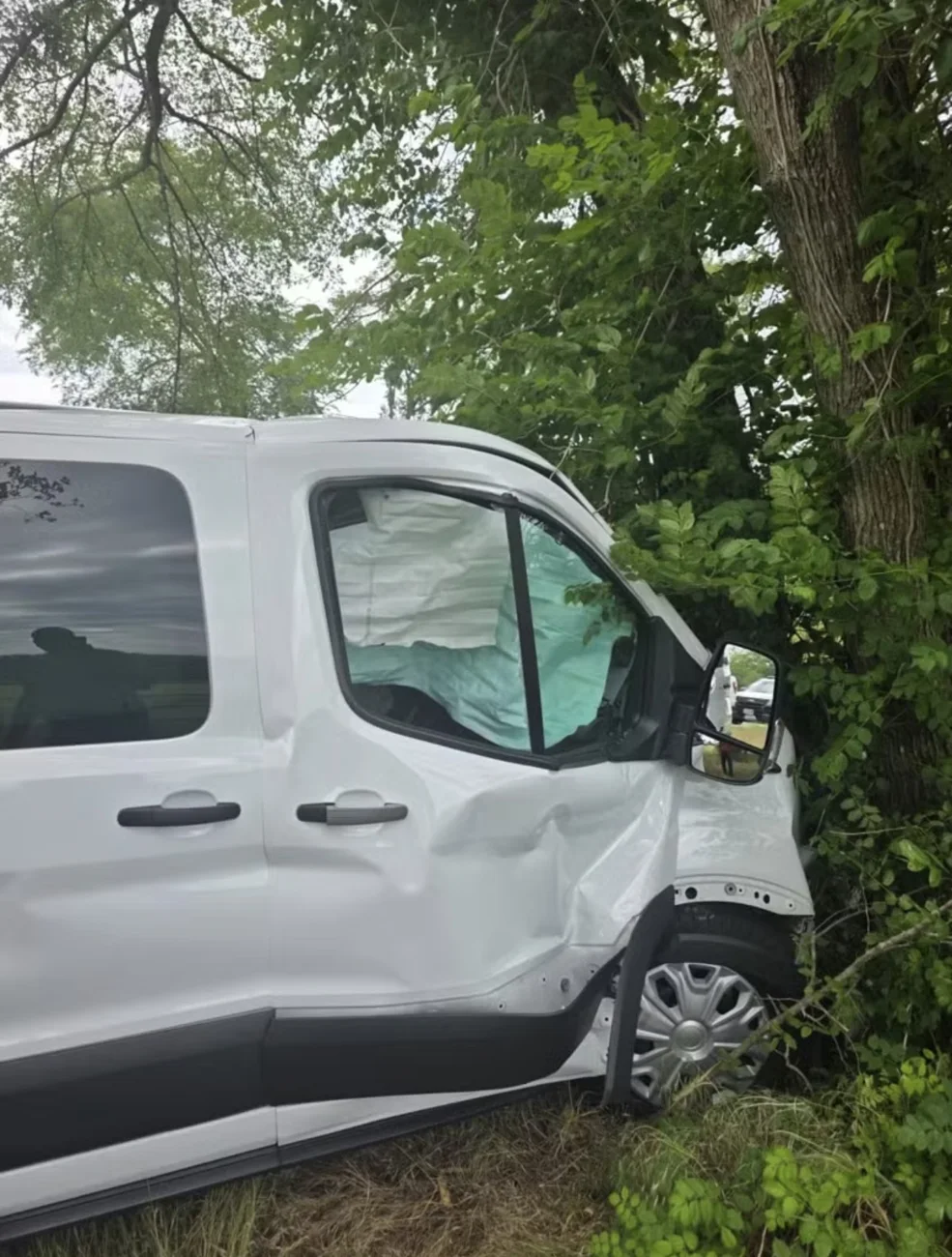 Passenger van side damage and deployed airbag documented after an incident