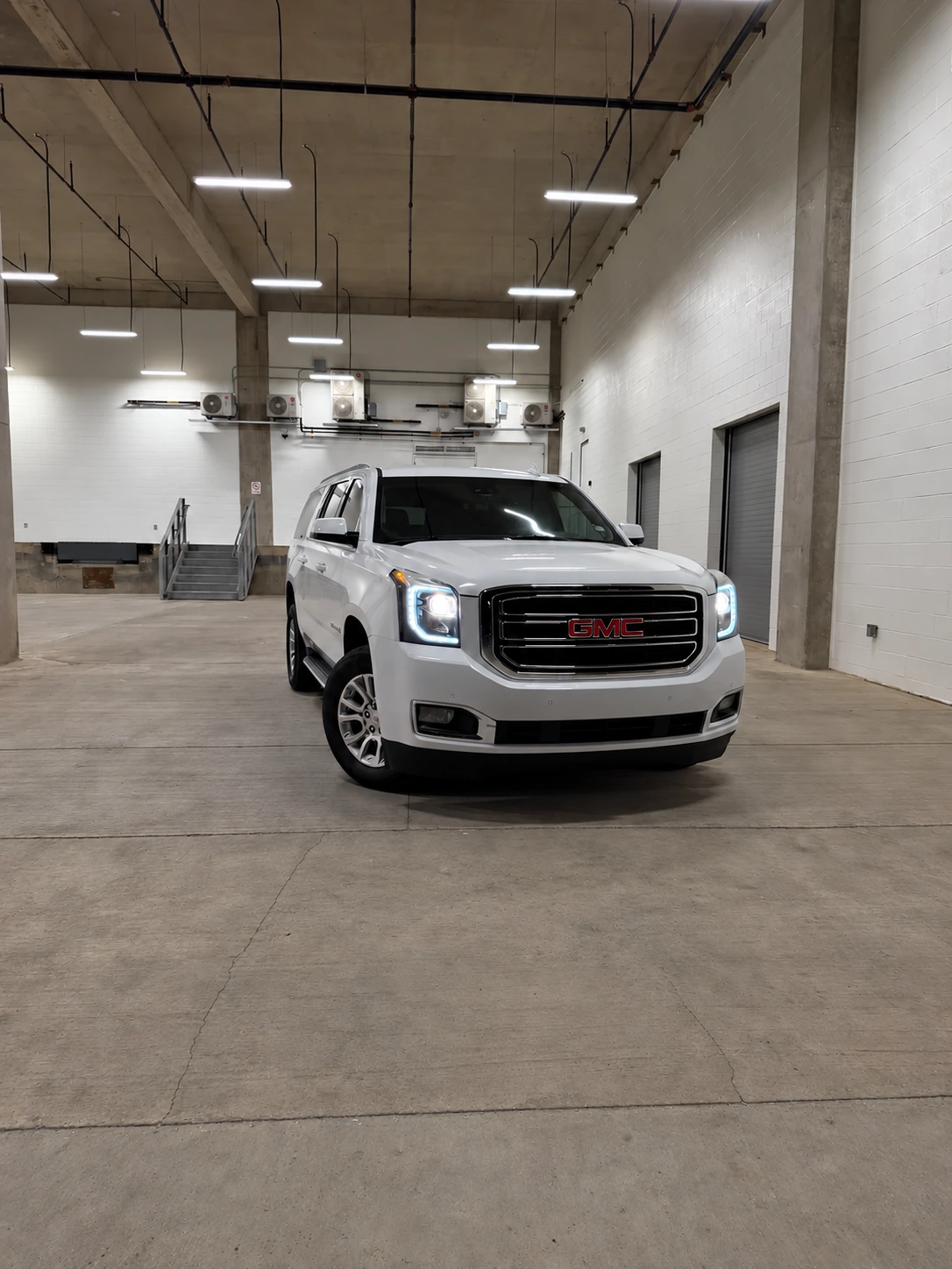 White GMC Yukon XL inside a vehicle preparation facility
